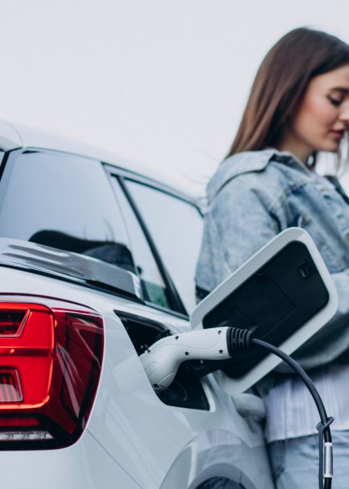 Woman charging her electric car with charging pistol